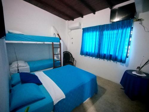 een slaapkamer met een blauw bed en blauwe gordijnen bij Hotel Cocos in Salinas