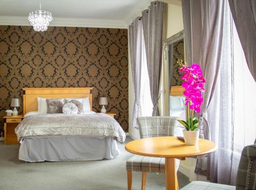 a bedroom with a bed and a table with a vase of flowers at Royal Hotel in Forfar