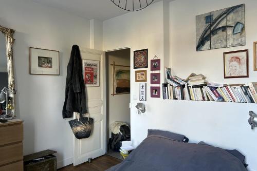 een slaapkamer met een bed en boeken aan de muur bij Spacious House - near Parc des Beaumonts in Montreuil