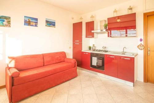 a red couch in a kitchen with red cabinets at Antonella in Campese