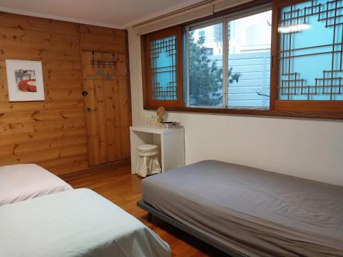 1 dormitorio con 2 camas, escritorio y ventanas en Art Residency en Busan