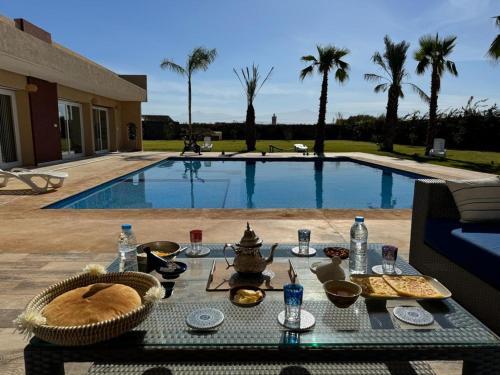 a table with food on it next to a swimming pool at Bienvenu chez VillAtlas in Marrakesh