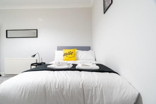 a white bedroom with a large white bed with a yellow pillow at Bell Apartment in Airdrie