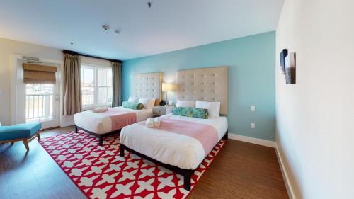 a bedroom with two beds and a red rug at The Hotel Maria in Westerly