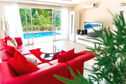 a living room with a red couch and a tv at Private Iberosta Villa Lagoon 4BDR, Beach, Pool - FREE GolfCart in May in Punta Cana