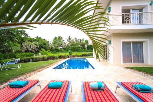 a villa with a swimming pool with red and blue chaises at Private Iberosta Villa Lagoon 4BDR, Beach, Pool - FREE GolfCart in May in Punta Cana