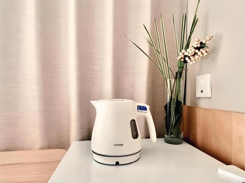 a coffee maker on a counter with a vase of flowers at 东京上野超级中心 设计师房间Yaob 上野公园3分钟 车站1分钟 超级繁华 免费wifi 戴森吹风 in Tokyo