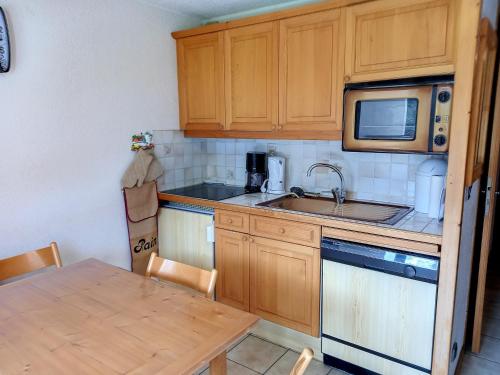 une petite cuisine avec un évier et un micro-ondes dans l'établissement Studio confortable Centre station Terrasse - FR-1-425-204, à Arâches-la-Frasse