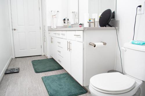 a bathroom with a toilet and two green mats on the floor at Midtown Contemporary Luxury 1BD-Pool-Gym-Patio-Office in Houston