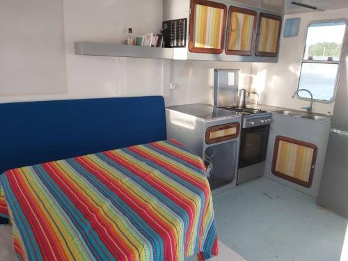a small kitchen with a colorful striped bed in a rv at L'aquahome hébergement sur l'eau in Les Trois-Îlets