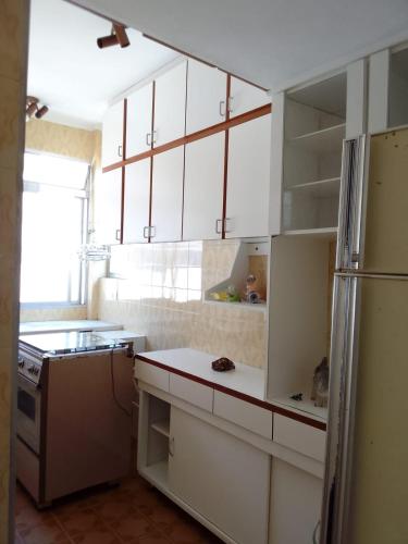 eine Küche mit weißen Schränken und einem Kühlschrank in der Unterkunft Kit Canto do Forte - Praia Grande in Praia Grande