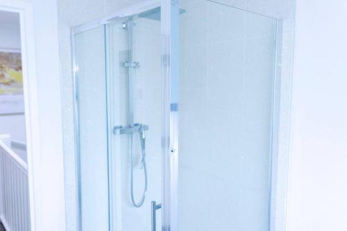 a shower with a glass door in a bathroom at Beautiful 3 bed house next to Westfield London in London