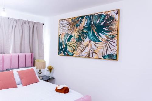 a bedroom with a bed and a painting on the wall at Beautiful 3 bed house next to Westfield London in London