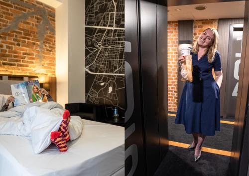 a woman drinking a cup of coffee next to a bed at Best Western Hotel Mariacki Katowice in Katowice