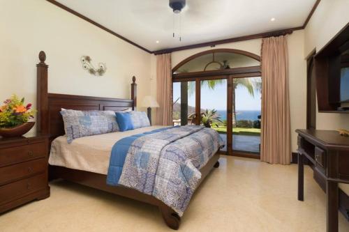 1 dormitorio con 1 cama y puerta corredera de cristal en Casa Cinco Sinsontes en Playa Hermosa