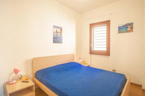 a bedroom with a blue bed and a window at Fortuna in Campese