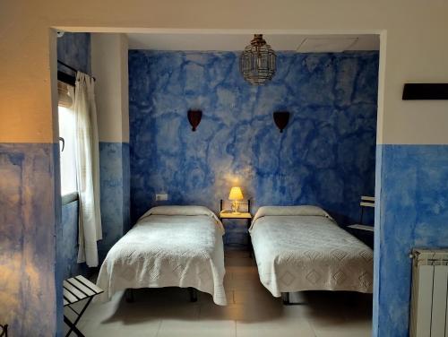 a bedroom with two beds and a blue wall at Hotel Finca Aldabra in Pinos Genil