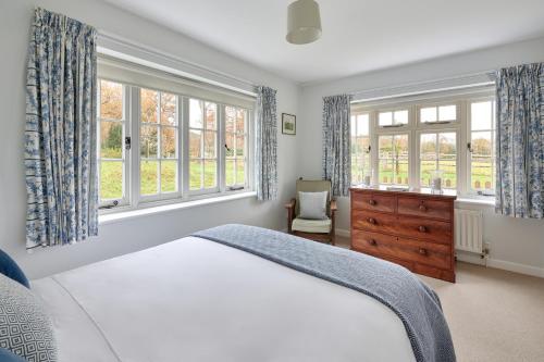 a bedroom with a bed and two windows and a dresser at Garden flat near Goodwood with stunning views in Petersfield