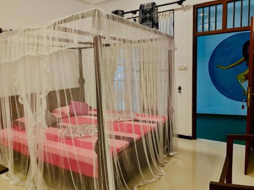 a room with a canopy bed with pink pillows at Gihan Guesthouse in Mirissa