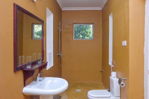 uma casa de banho com um lavatório, um WC e um espelho. em Pearl Beach by Sansi em Michamvi