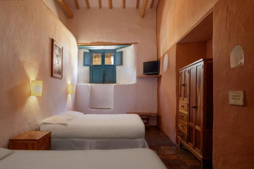 een kleine slaapkamer met 2 bedden en een raam bij Posada del Campanario in Barichara