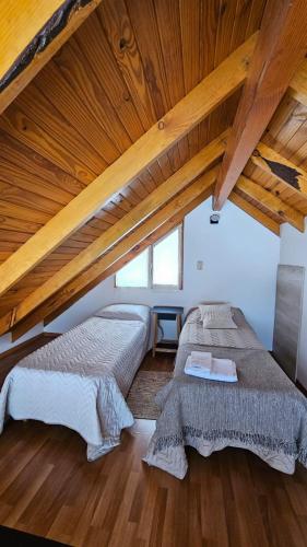 two beds in a attic room with wooden ceilings at La casita suereña in Esquel