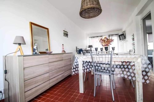 une salle à manger avec une table, des chaises et un miroir dans l'établissement Ste Cécile Plage, à Camiers