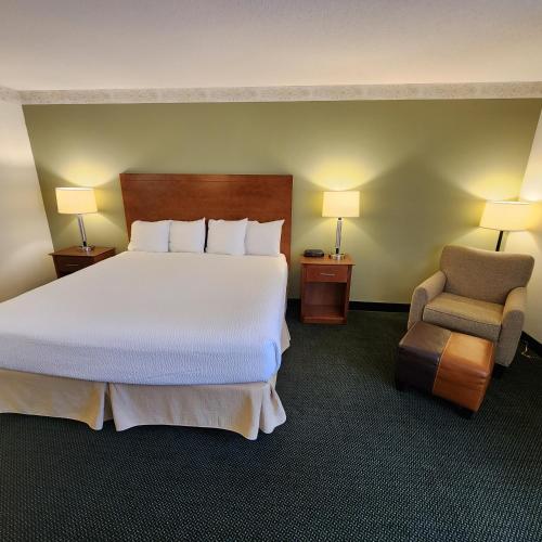a hotel room with a large bed and a chair at Baymont by Wyndham Mackinaw City in Mackinaw City