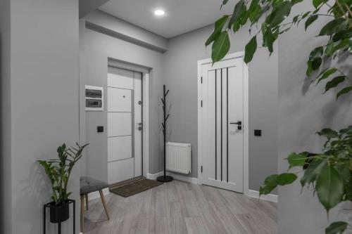 um corredor com paredes brancas e uma porta com uma planta em Flatkeepers - Toro Center em Chisinau