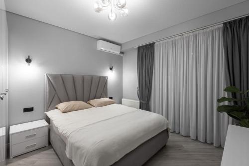 Habitación blanca con cama grande y lámpara de araña. en Flatkeepers - Toro Center, en Chişinău
