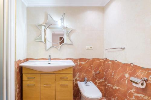 a bathroom with a sink and a toilet and a mirror at Los Pinos 9B Apartment Levante Beach-Old Town in Benidorm