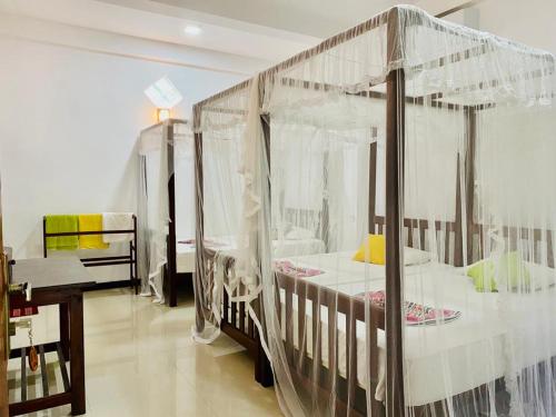 a bedroom with a canopy bed with curtains at Gihan Guesthouse in Mirissa