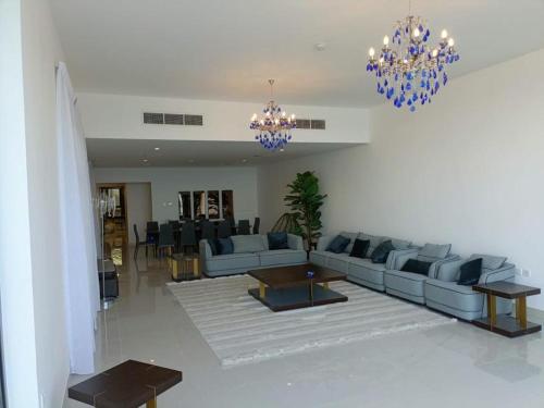 a living room with a couch and a table and chandeliers at Oceanfront Villa 5BHK with private pool and seaview in Fujairah