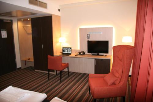 a hotel room with a desk and a chair and a television at Hotel Fortune in Cologne