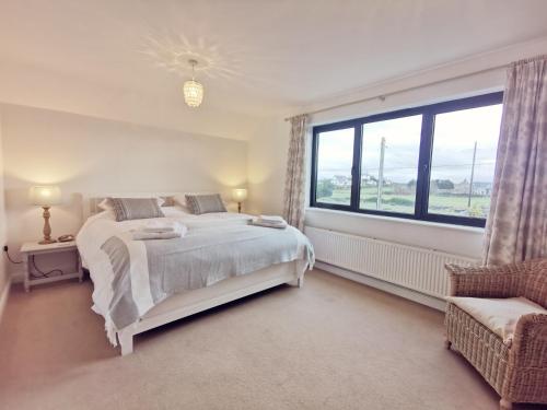 a white bedroom with a bed and a large window at TULLOCHSIDE-4 BED-SEA FRONT -RAVENSPOINT ROAD in Trearddur