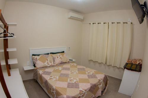 um pequeno quarto com uma cama e uma janela em Apartamento encantador próximo praia mercado Farm padaria em Imbituba