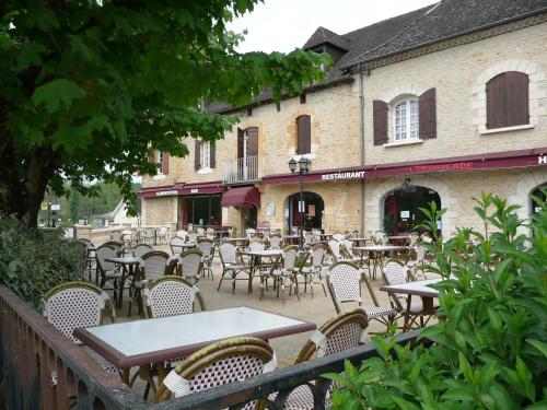 an outdoor patio with tables and chairs and a building at Hotel Restaurant L'Escale in Sainte-Nathalène