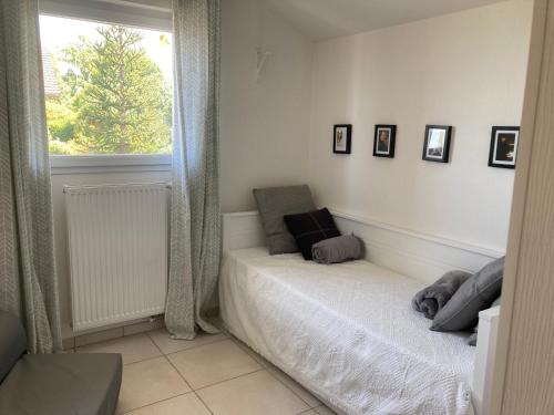 Habitación blanca con cama y ventana en Appartement de charme sur les Hauts d'Evian, en Évian-les-Bains
