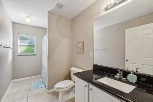 a bathroom with a sink and a toilet and a mirror at Pet-Friendly Cape Coral Retreat with Screened Porch! in Cape Coral