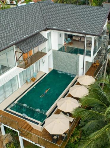 an aerial view of a house with a swimming pool with umbrellas at Beacon By The Bay Villas and Suites by the Clarks in Matara