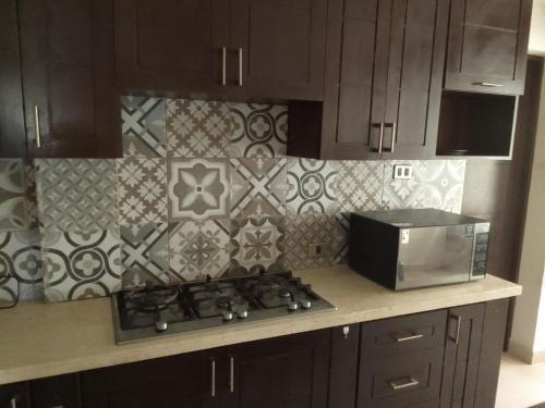a kitchen with a stove and a microwave at Linda casa de campo con todas las comodidades de la ciudad in Cochabamba