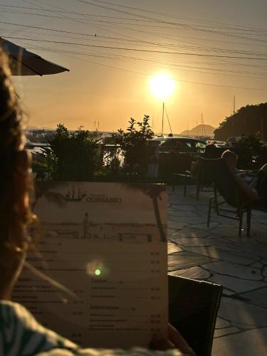 a person sitting at a table watching the sunset at Pousada Corsario Buzios in Búzios