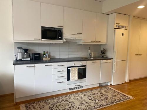 a kitchen with white cabinets and a white refrigerator at Parvekkeellinen moderni asunto in Turku