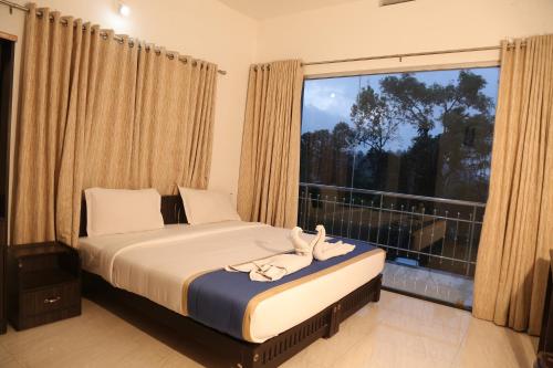 a bedroom with a bed and a large window at Nandana's Residency Munnar in Munnar