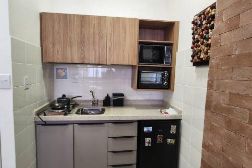 uma pequena cozinha com fogão e micro-ondas em Seu Lugar em Beagá em Belo Horizonte