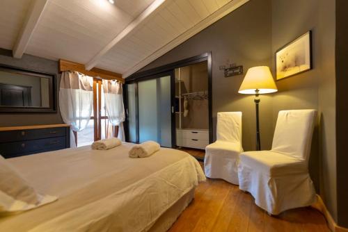 a bedroom with a bed and two white chairs at Casa Vacanza La Perla in Villanova Mondovì