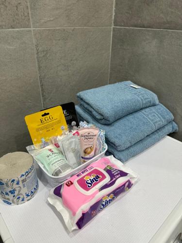 a bathroom counter with toiletries and towels on it at Лазурный Квартал in Astana