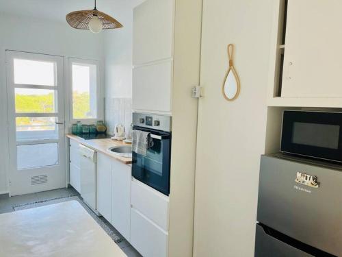 eine weiße Küche mit einer Spüle und einer Mikrowelle in der Unterkunft Vue mer Appartement Le Miramar in La Baule