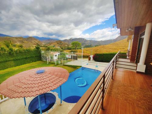 einen Balkon mit Sonnenschirm und Pool in der Unterkunft Quinta Esperanza in Loja