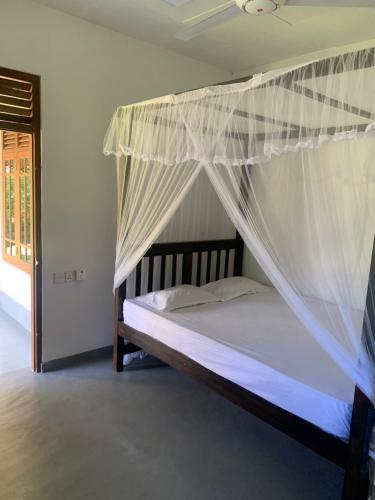 a bedroom with a bed with a mosquito net at Original track by Unrushed in Weligama